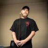 black kaine cues logo t-shirt worn by a team member against a neutral background.